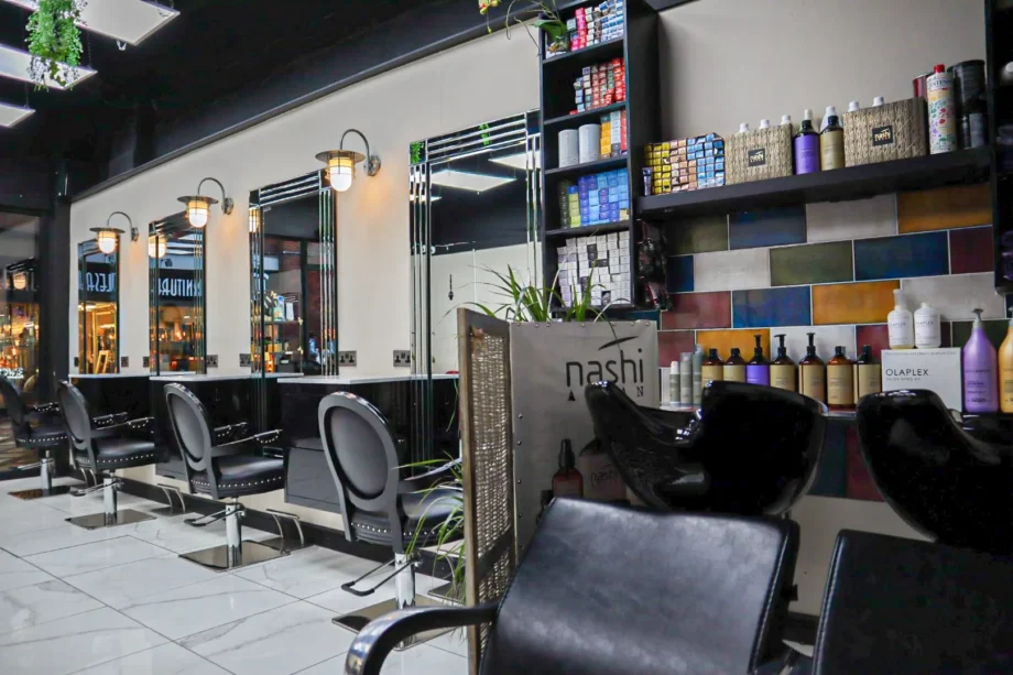 Inside of shop with a line of hairdressing chairs and waiting seats.