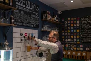 Image of shop owner pouring beer of 7000 Jars of Beer Off License in Kingston Upon Thames