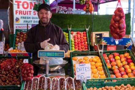 A range of fresh fruit and veg with man bending over to pick something up.